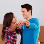 Gastos de compra de vivienda: ¿Cuánto deberías ahorrar antes de comprar? 6 Pareja joven con las llaves de su casa gracias al aval hipotecario para jóvenes en Galicia